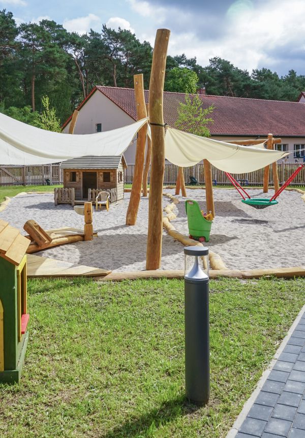 Sicht auf den Spielplatz, im Vordergrund ein kleines, grünes Spielhaus