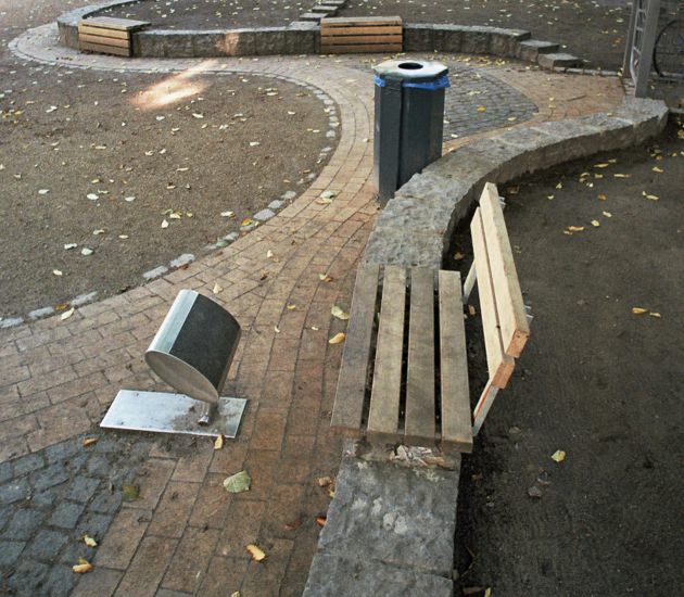 Parkbegrenzung durch Pflastersteinmauer und eingebettenten Holzbänken