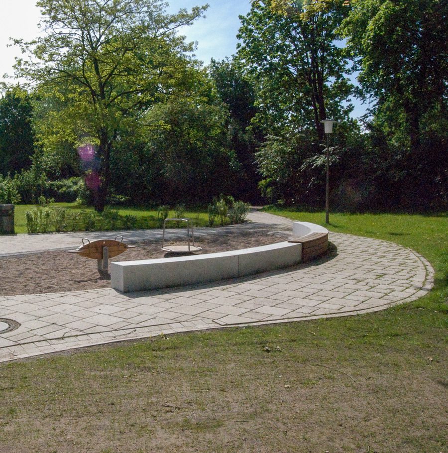 Spielplatz mit Sitzgelegenheit und Grünfläche im Hintergrund