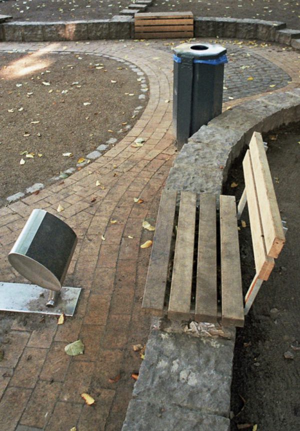 Parkbegrenzung durch Pflastersteinmauer und eingebettenten Holzbänken