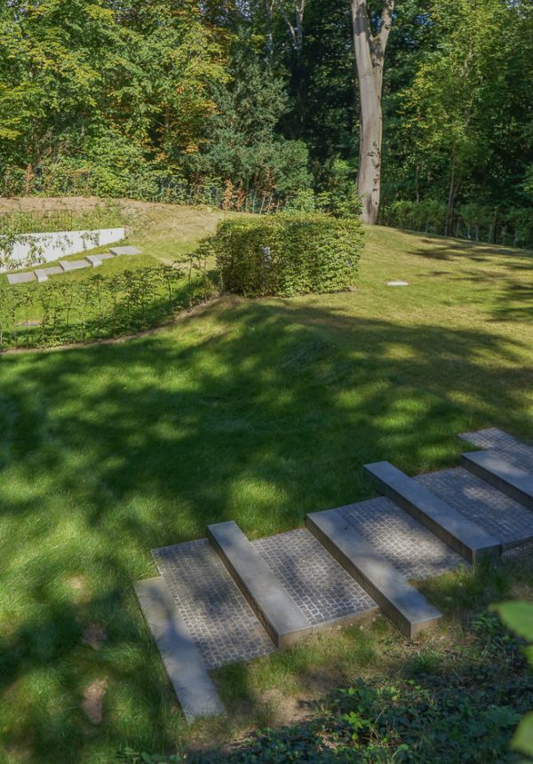 grüne Gartenterrasse auf mehreren Höhenbenen, die durch eine flache Treppe, aus rhytmisch angeordneten Steinmodulen, verbrunden wird